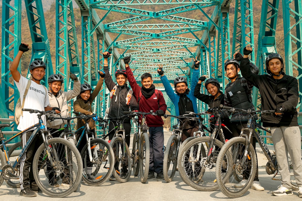a group of people standing next to bikes on a bridge