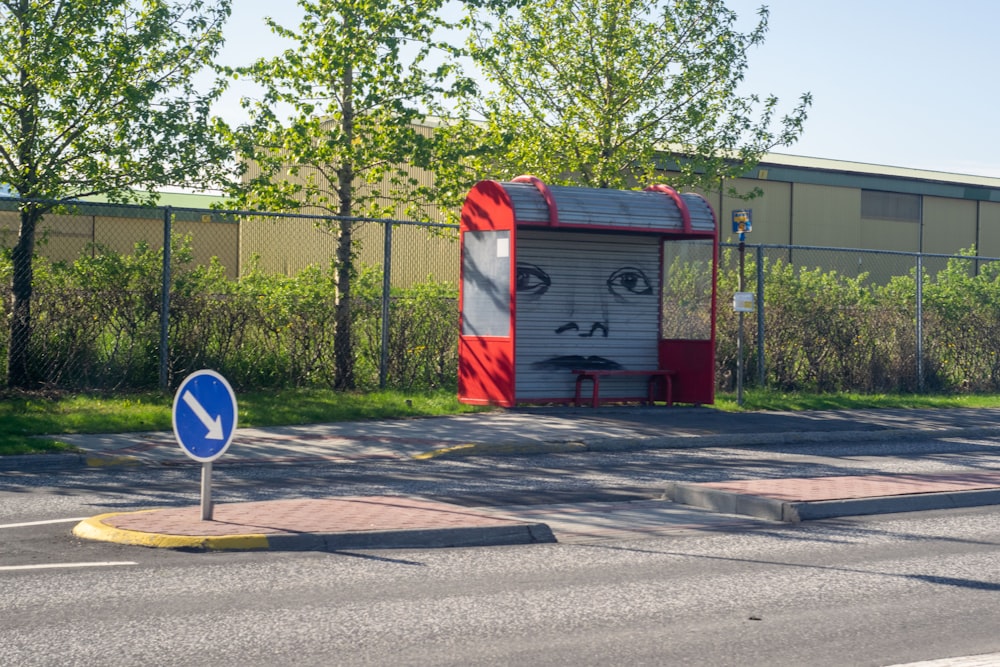 a red and white box sitting on the side of a road