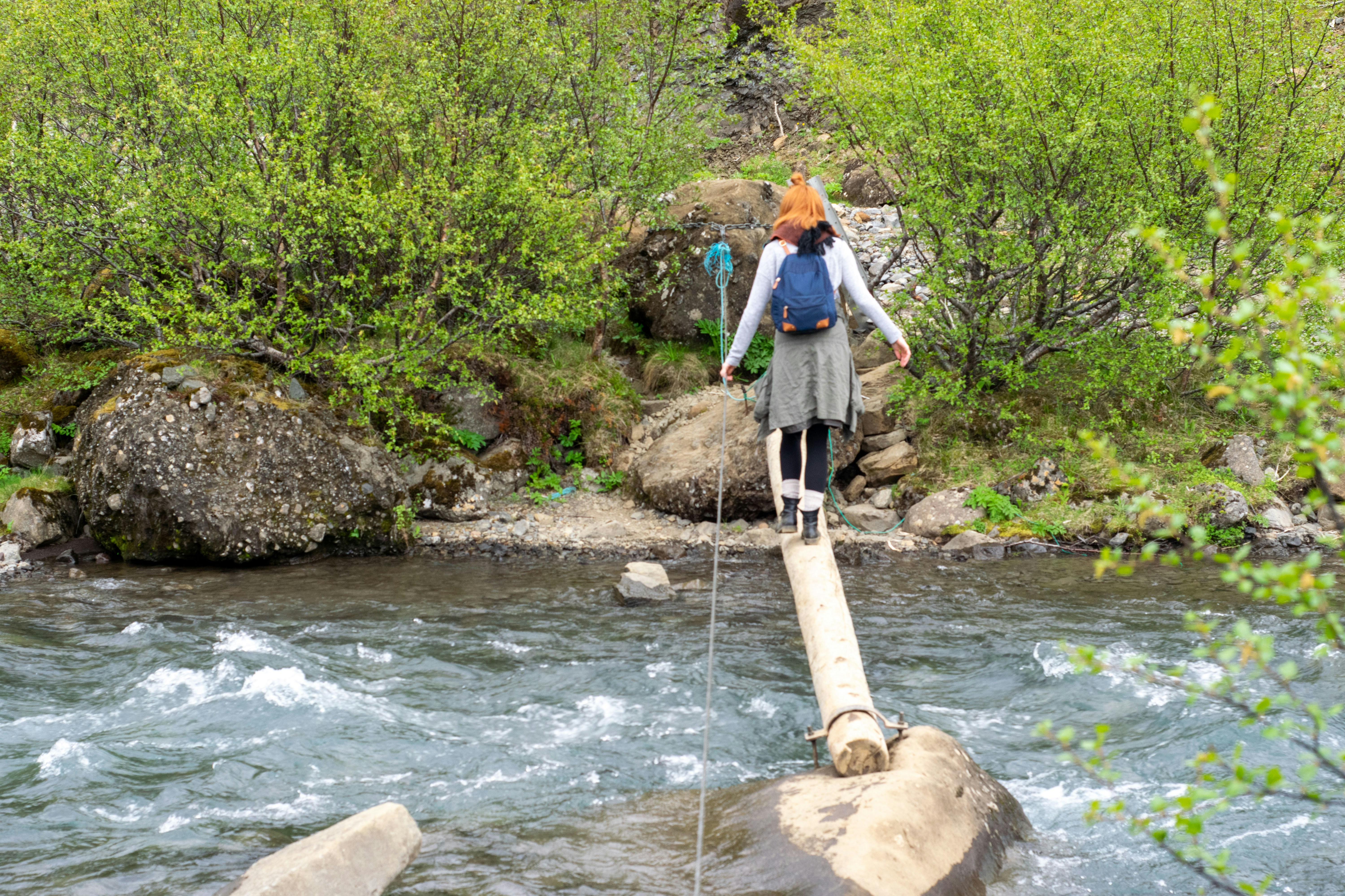 a woman walking across a wooden bridge over a river