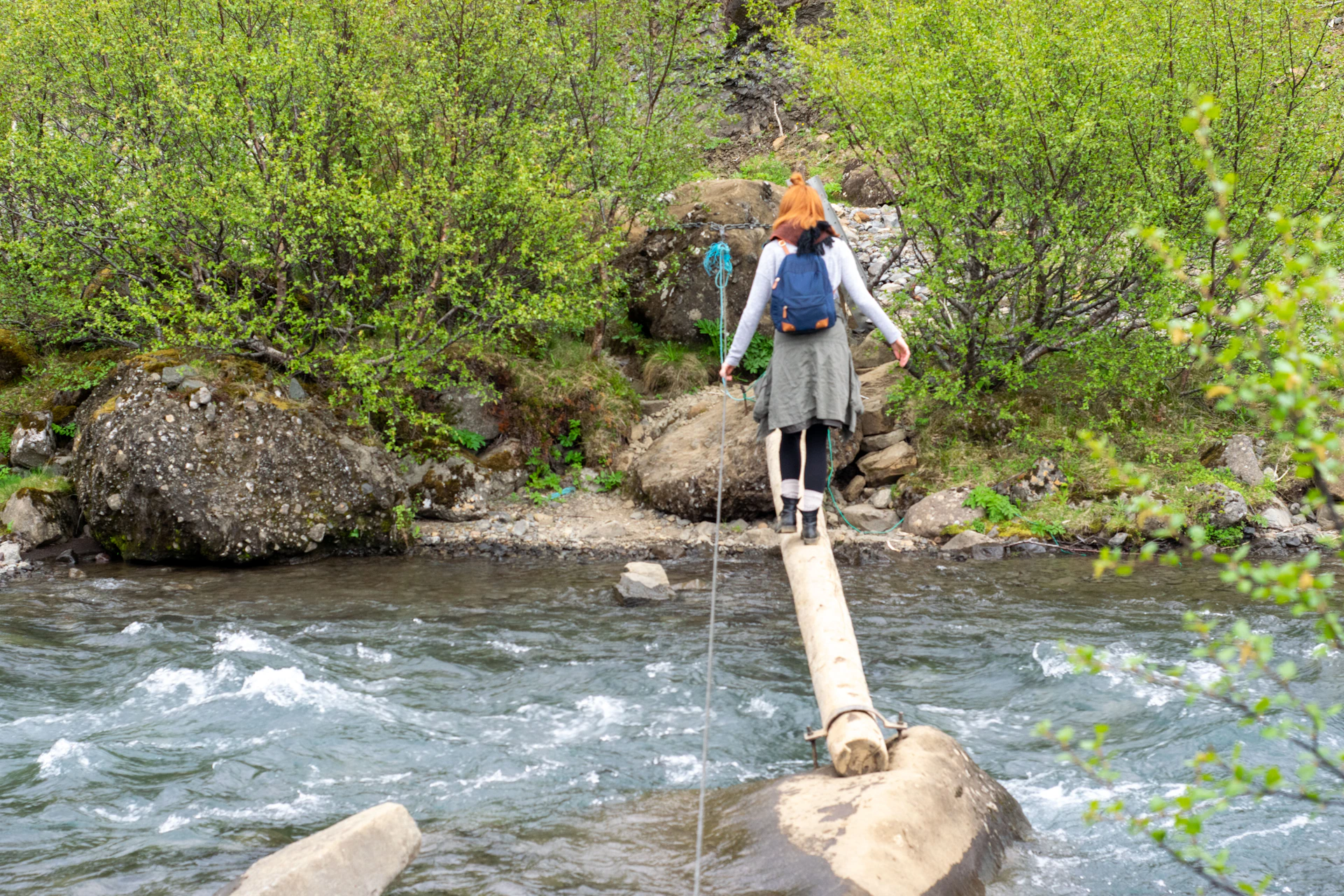 a woman walking across a wooden bridge over a river