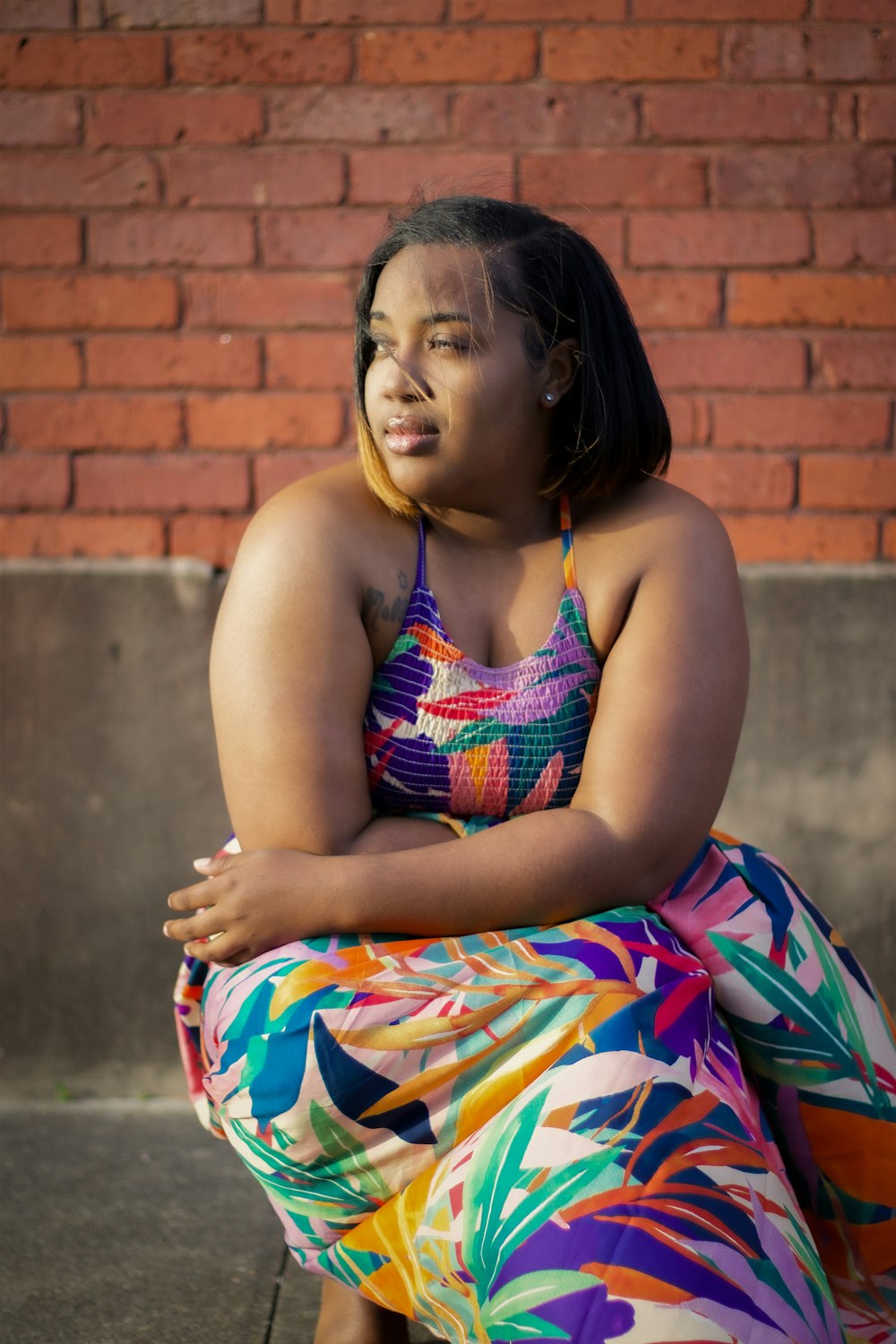 a woman in a colorful dress sitting on a curb