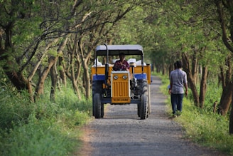 a man driving a tractor down a dirt road