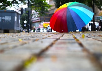 A colorful umbrella open against a rainy city street backdrop.
