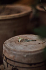Close-up of natural textures; terracotta pots and soft beige fabrics on a rustic wooden table.