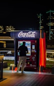 a man standing in front of a coca cola machine