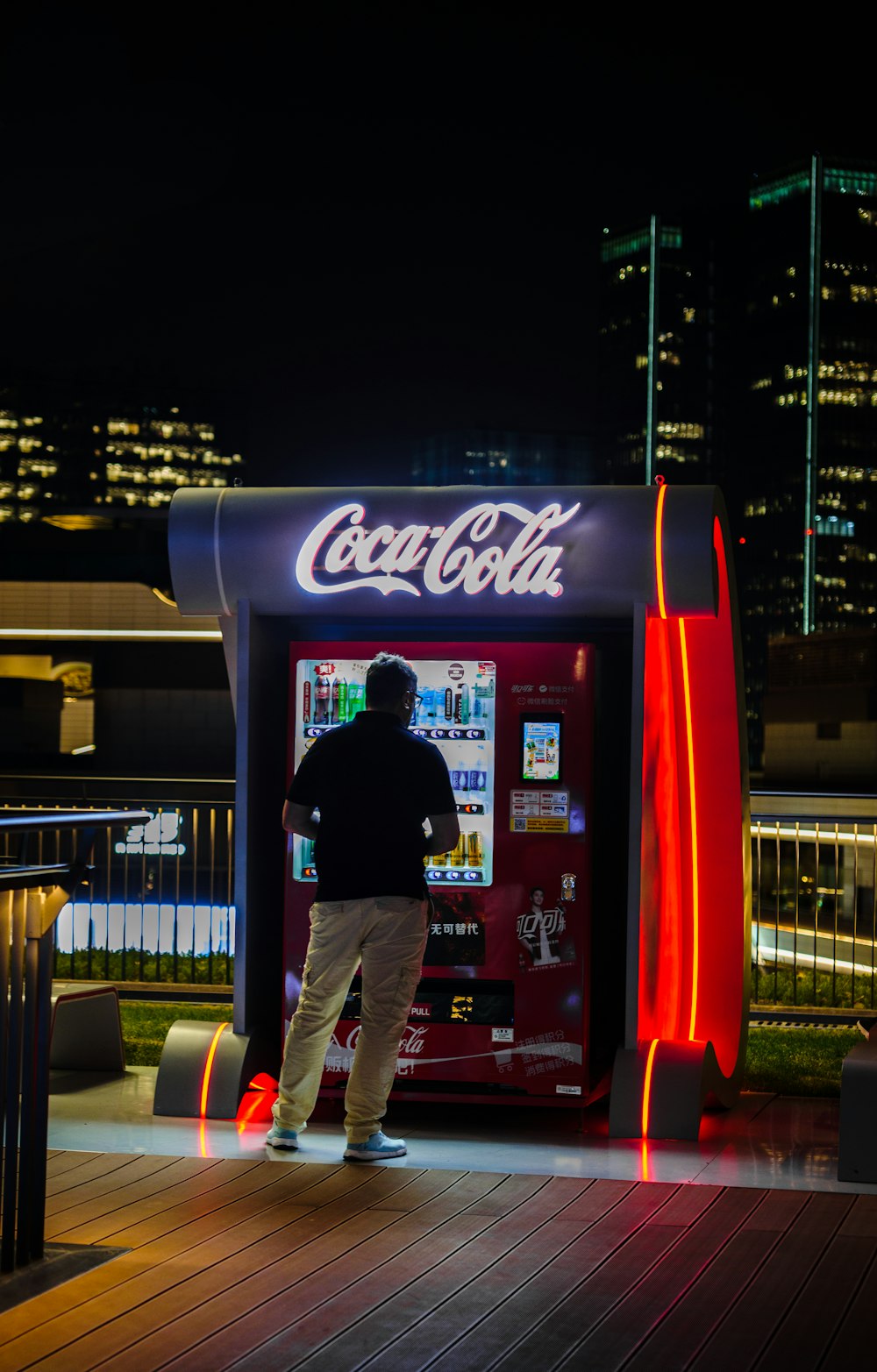 a man standing in front of a coca cola machine