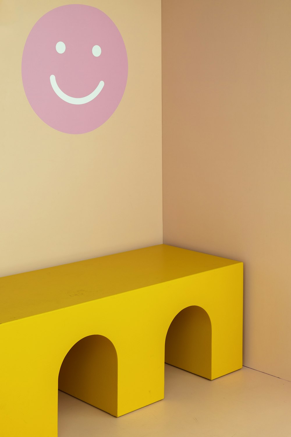 a yellow bench with a smiley face painted on the wall