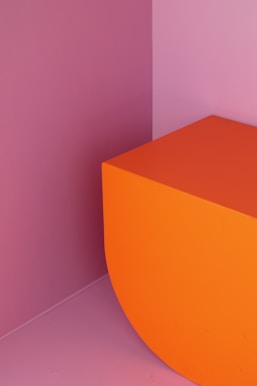an orange bench in a room with a pink wall