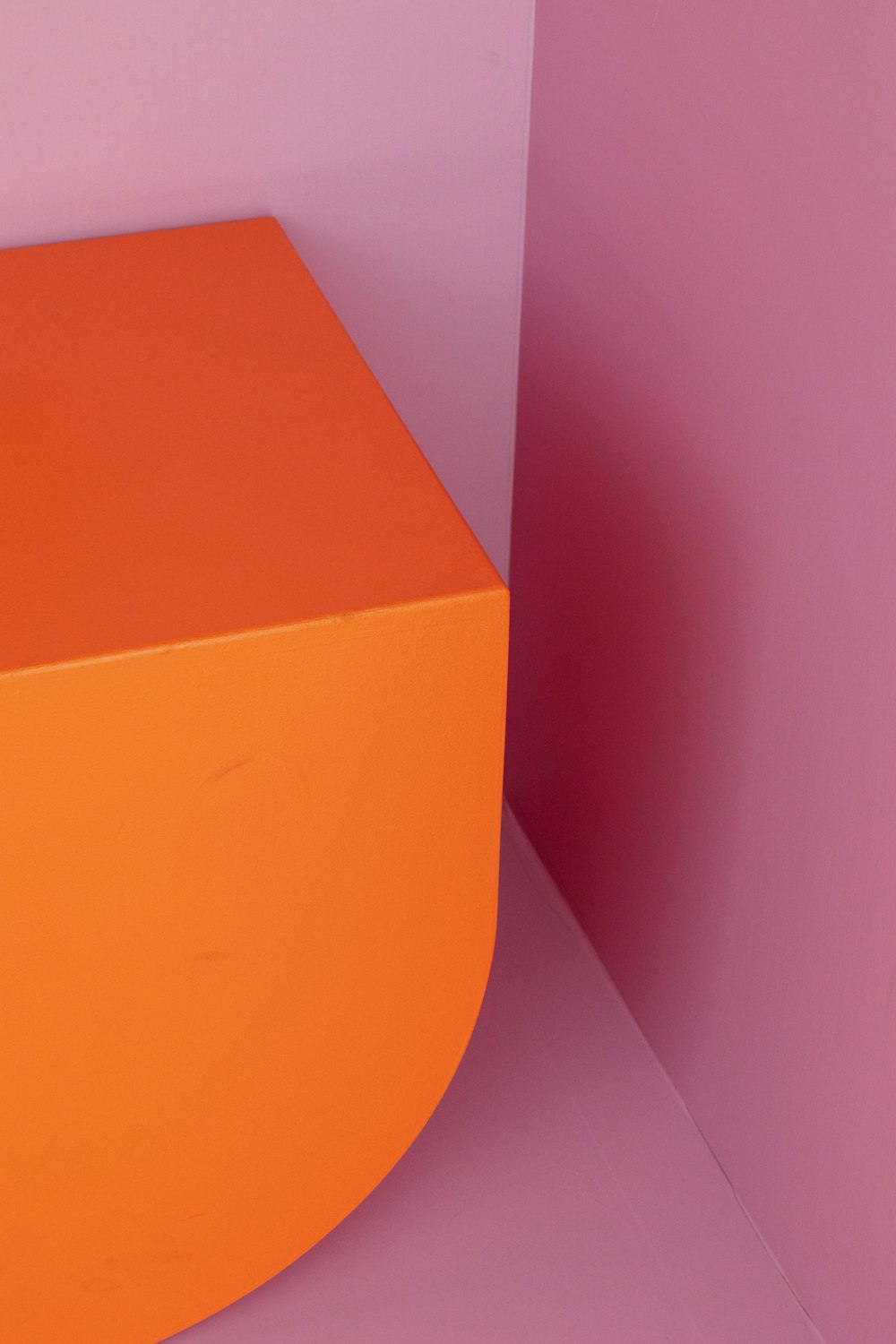 an orange box sitting on top of a pink wall