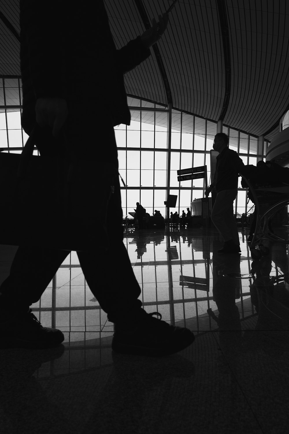 a black and white photo of a person walking through an airport