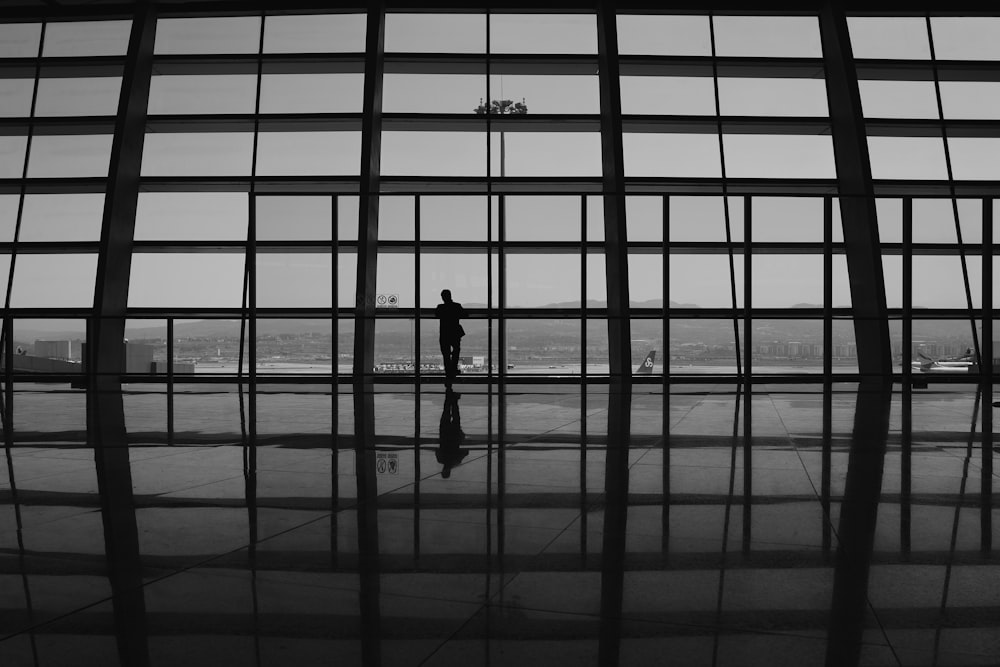 ein Schwarz-Weiß-Foto einer Person, die auf einem Flughafen steht