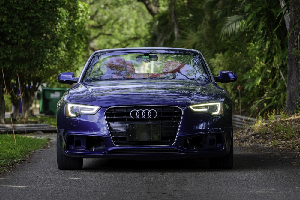 a blue car driving down a road next to trees