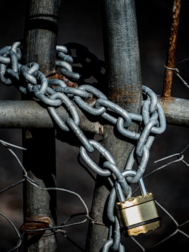 A padlock securing a chain-link fence, illustrating the layered physical barriers that protect against precious metals theft