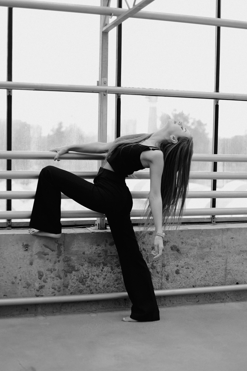 a woman in a black top is leaning on a wall