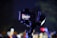 A camera mounted on a stabilizer is capturing a scene. The screen on the camera displays a colorful crowd with bright lighting, suggesting an event or performance is taking place.