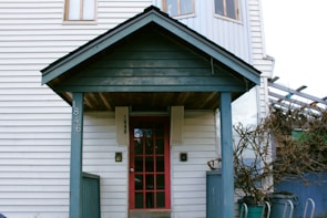A modern porch featuring tall green plants in sleek ceramic pots by the door.