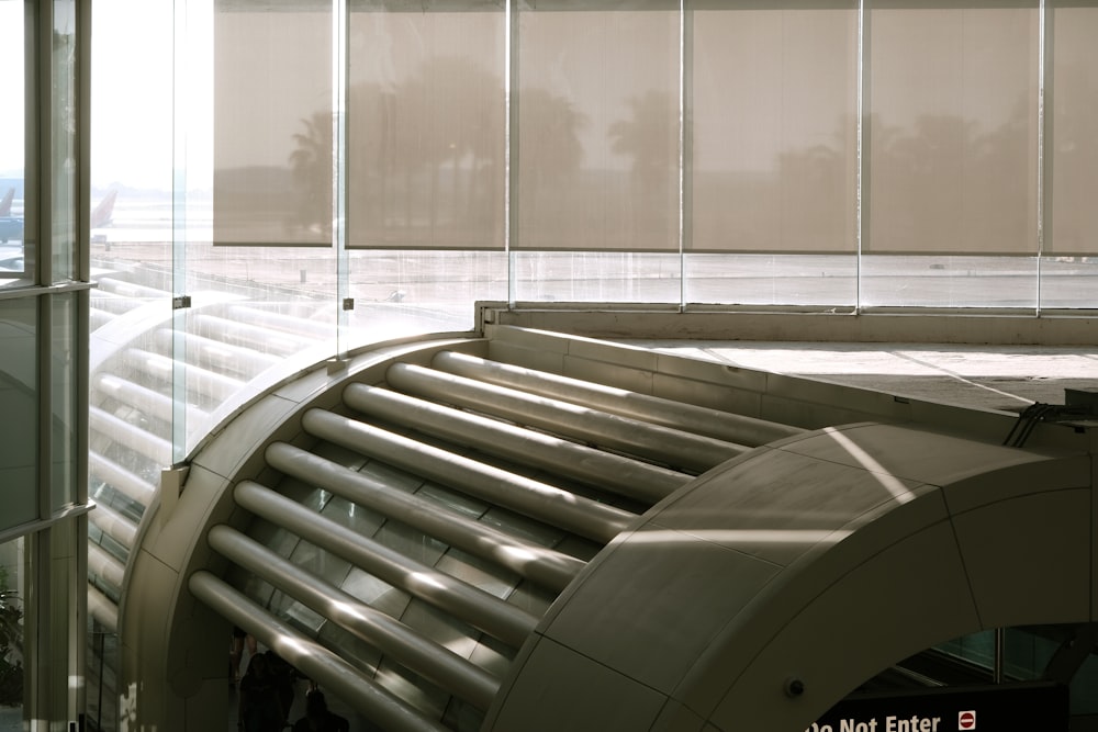a curved metal and glass walkway in an airport