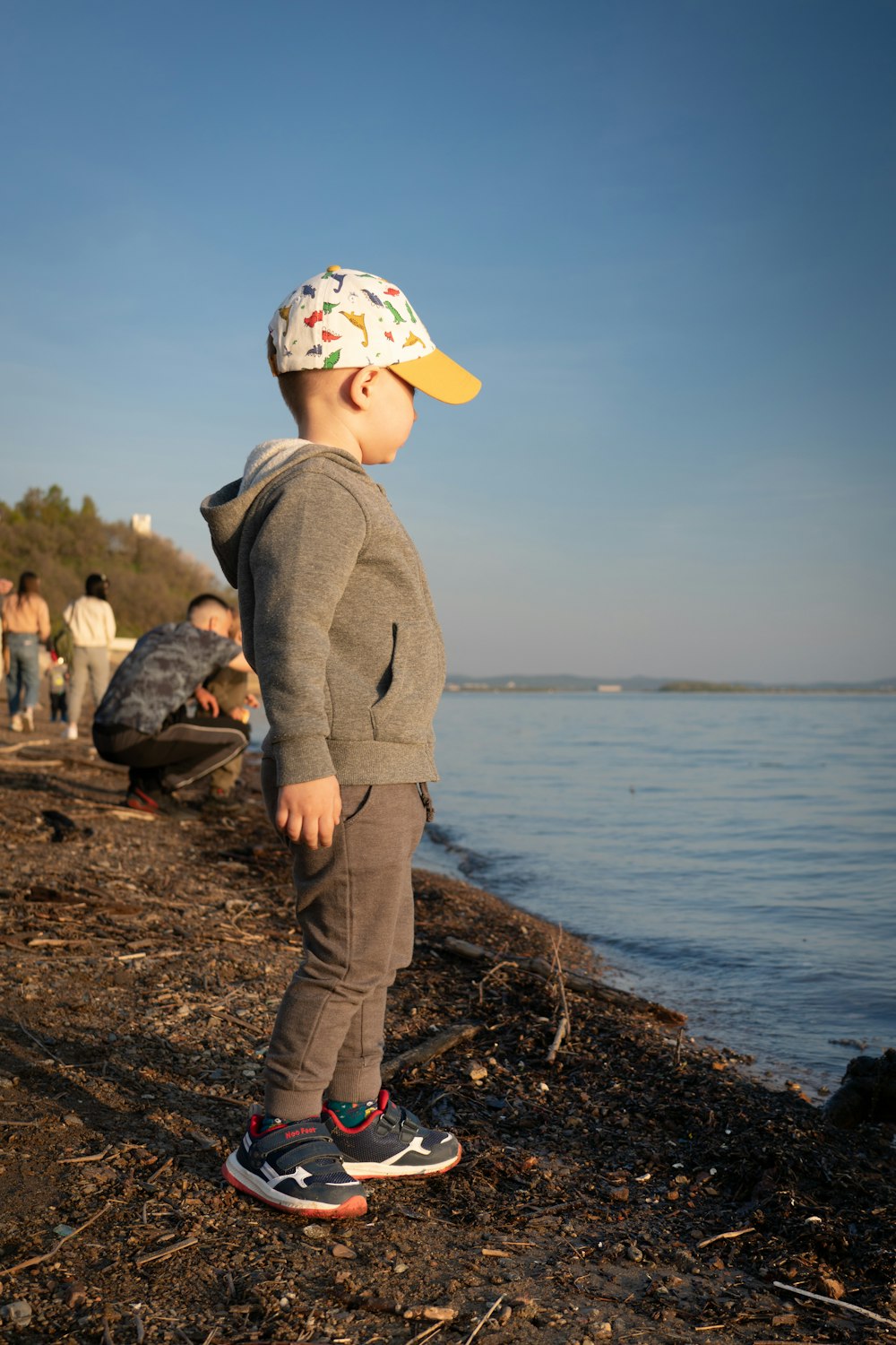 a little boy standing on top of a beach next to the ocean