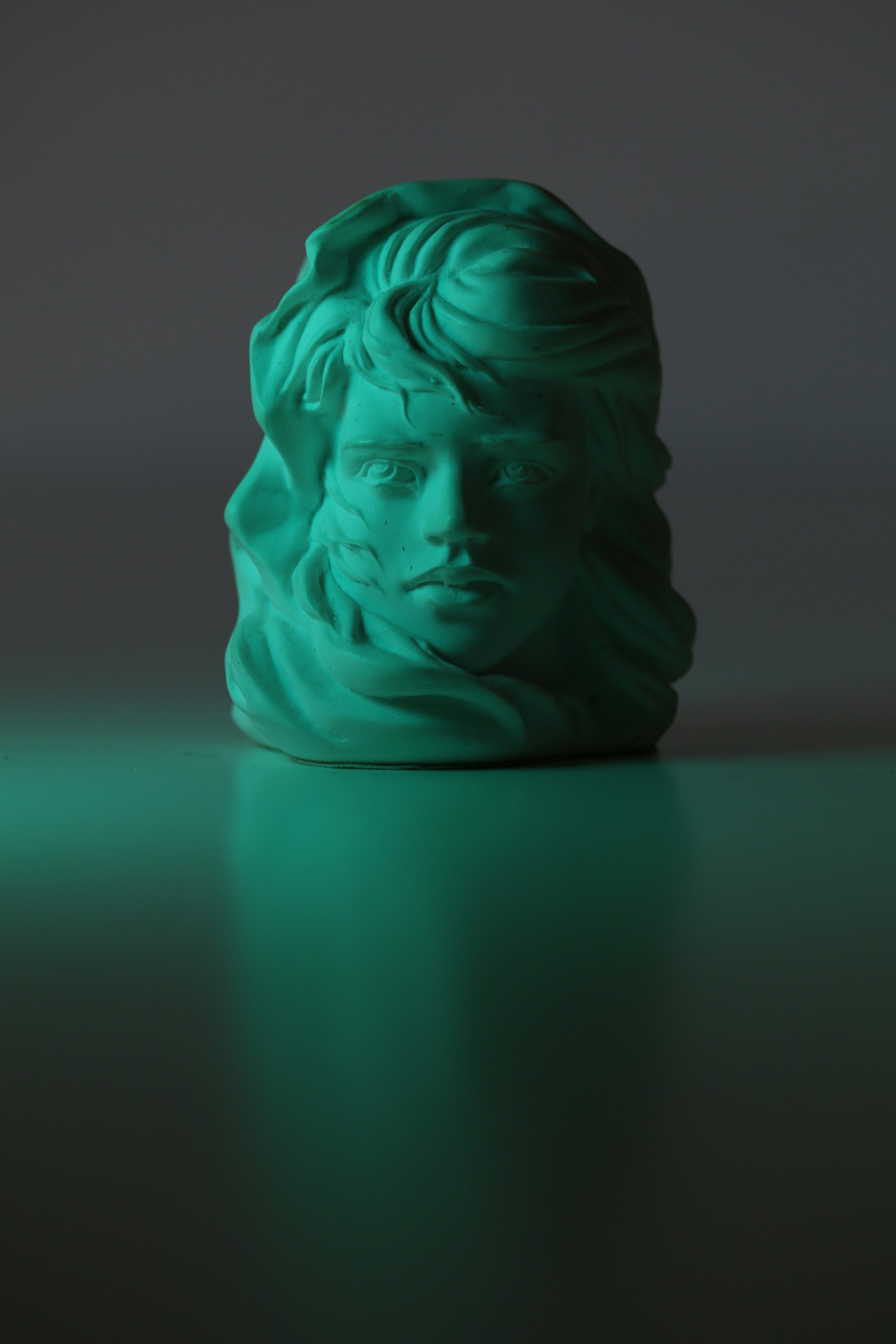 a green sculpture of a man's head on a table