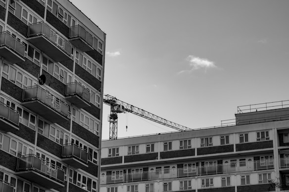 High-rise residential buildings with balconies and a construction crane in the background. The image is in black and white, giving it a classic and urban vibe.