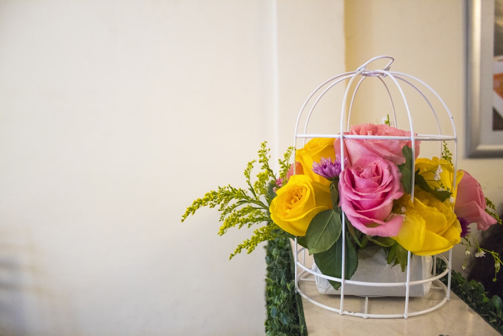 a birdcage with a bunch of flowers inside of it