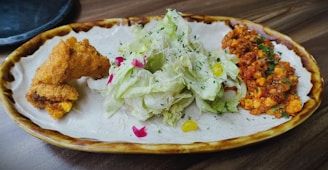 An inviting dinner plate with Kerala-style chicken roast, parotta, and a side of fresh salad.