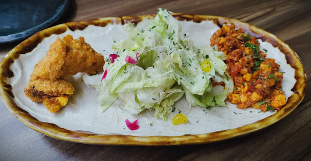 A vibrant plate of butter chicken with naan bread and fresh salad.