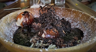 A bowl of creamy cookie dough topped with chunks of chocolate and a drizzle of caramel sauce.