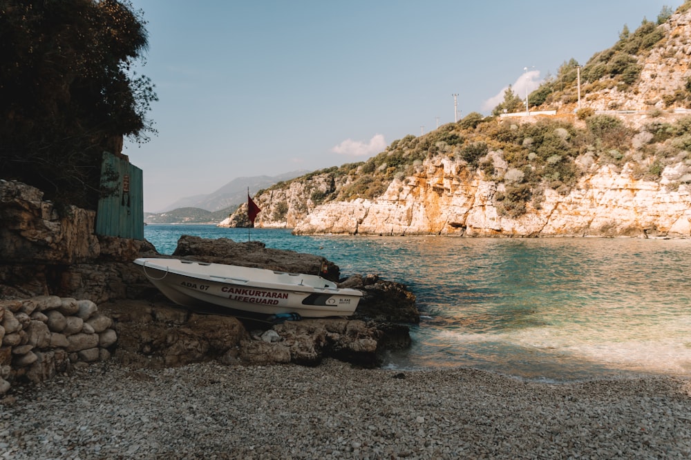 a boat sitting on a rocky shore next to a body of water