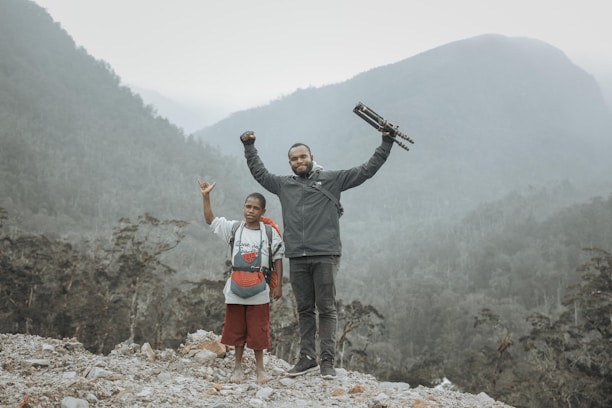 A candid photo of the FootlooseArther duo smiling beside a rugged mountain trail.