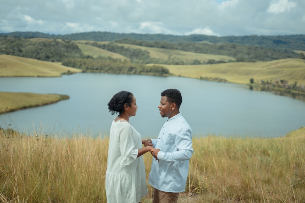a man and woman standing in front of a lake
