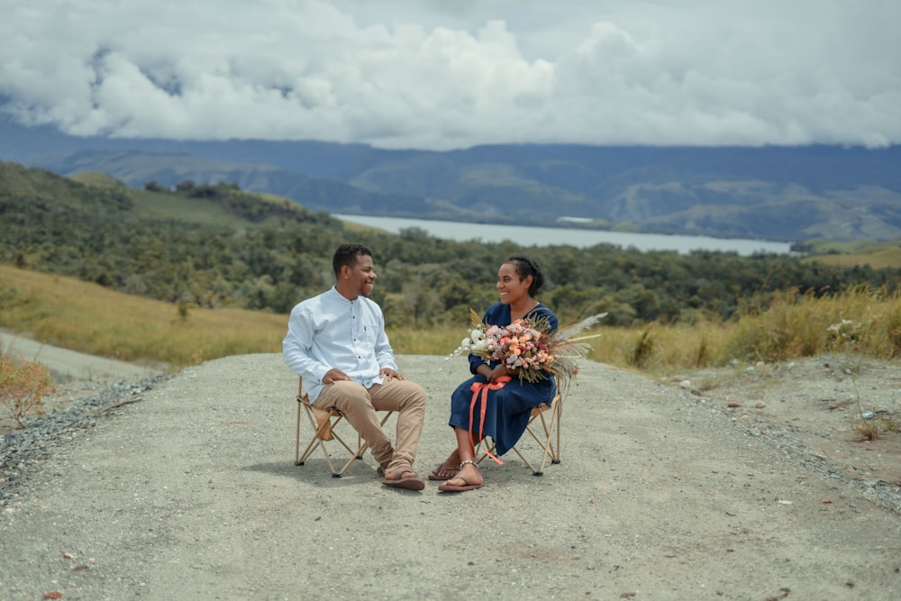 a man and woman sitting on a chair on a dirt road