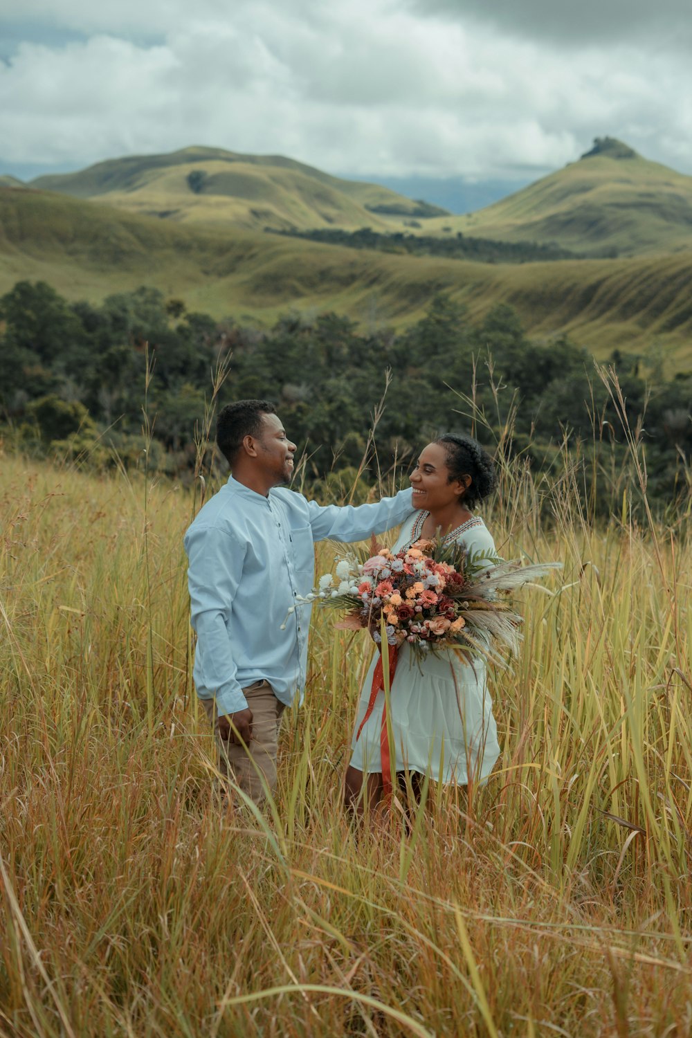 a man and a woman standing in tall grass