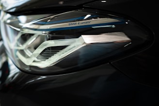 Close-up of a sleek car headlight featuring intricate design details and metallic accents. The headlight is part of a modern vehicle with a sophisticated lighting system, indicated by the 'BMW Laser' branding.