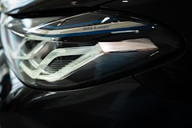 Close-up of a sleek car headlight featuring intricate design details and metallic accents. The headlight is part of a modern vehicle with a sophisticated lighting system, indicated by the 'BMW Laser' branding.