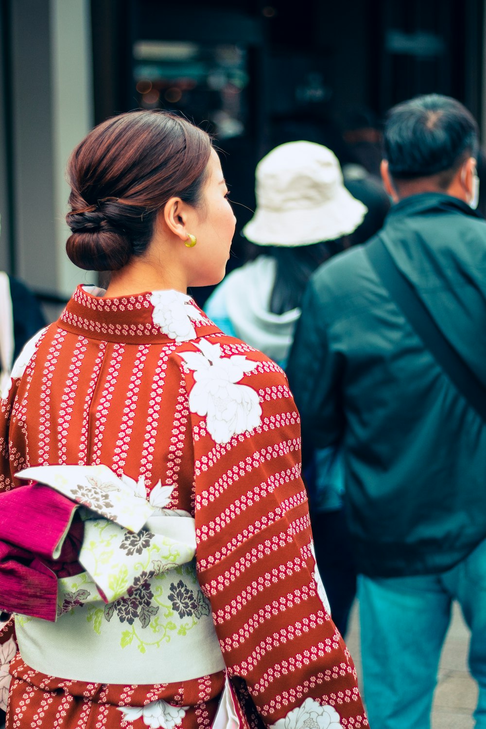 a woman in a red and white kimono walking down a street
