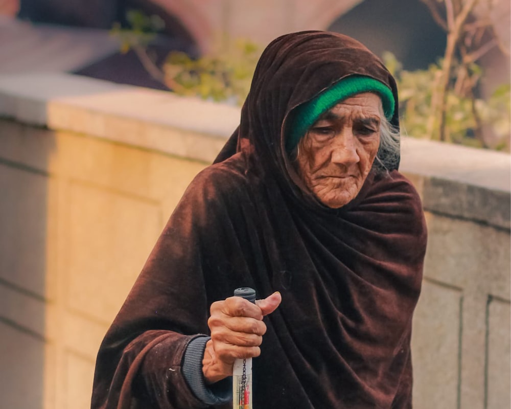 an old woman in a brown robe holding a cane