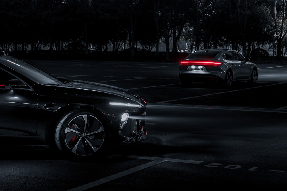 two cars parked in a parking lot at night