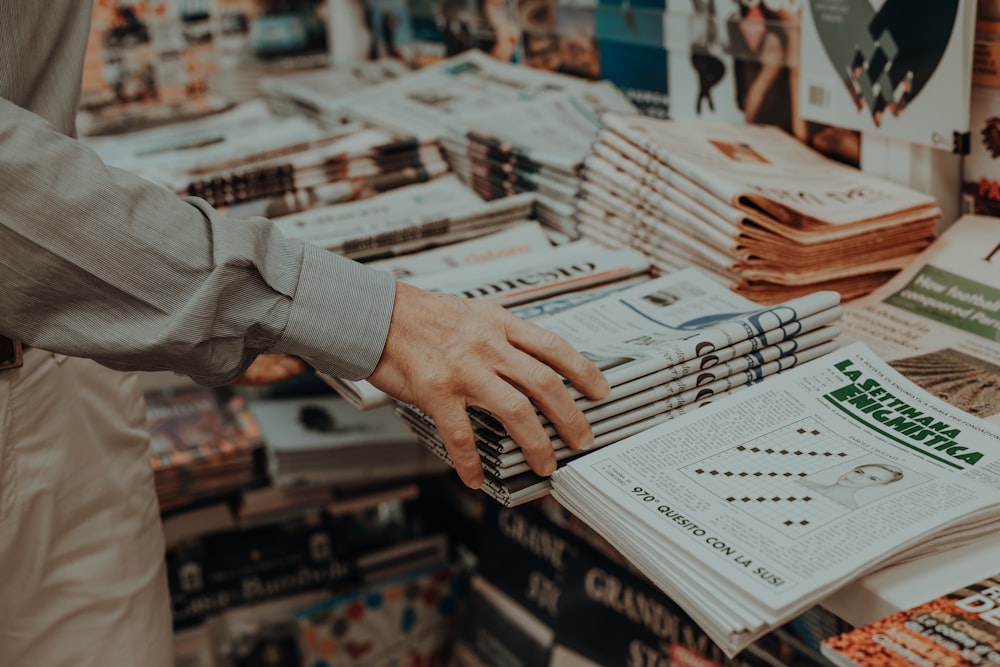 a person is holding a stack of magazines