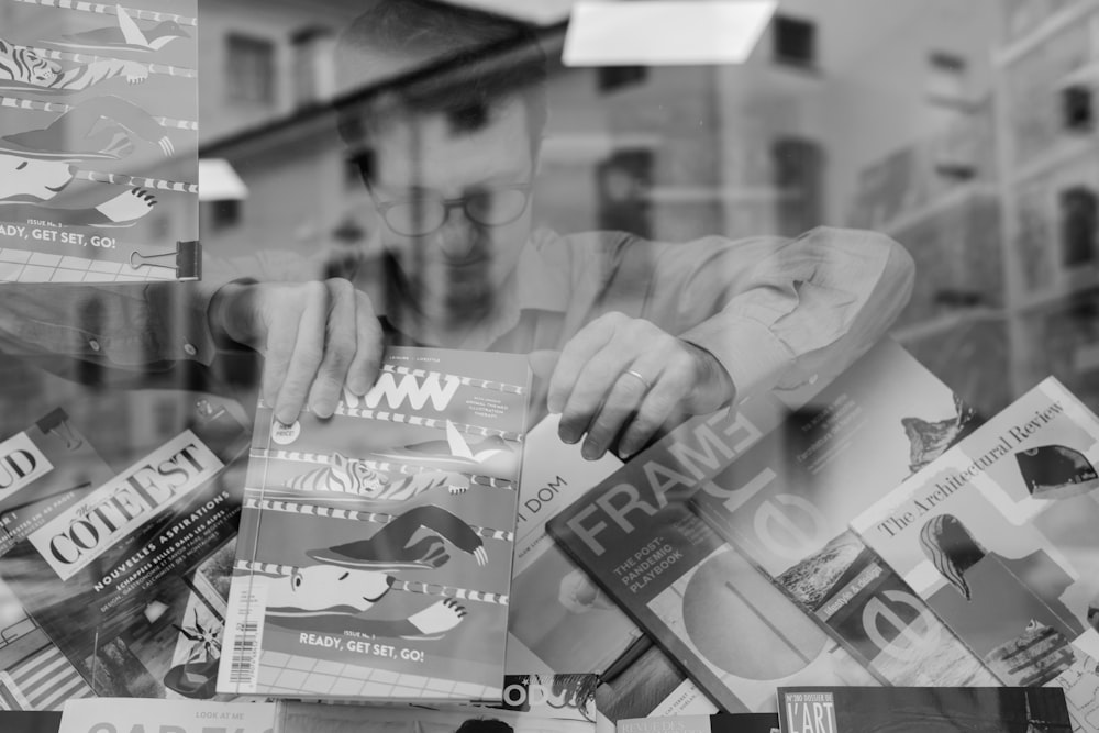 a man holding a magazine in front of a window