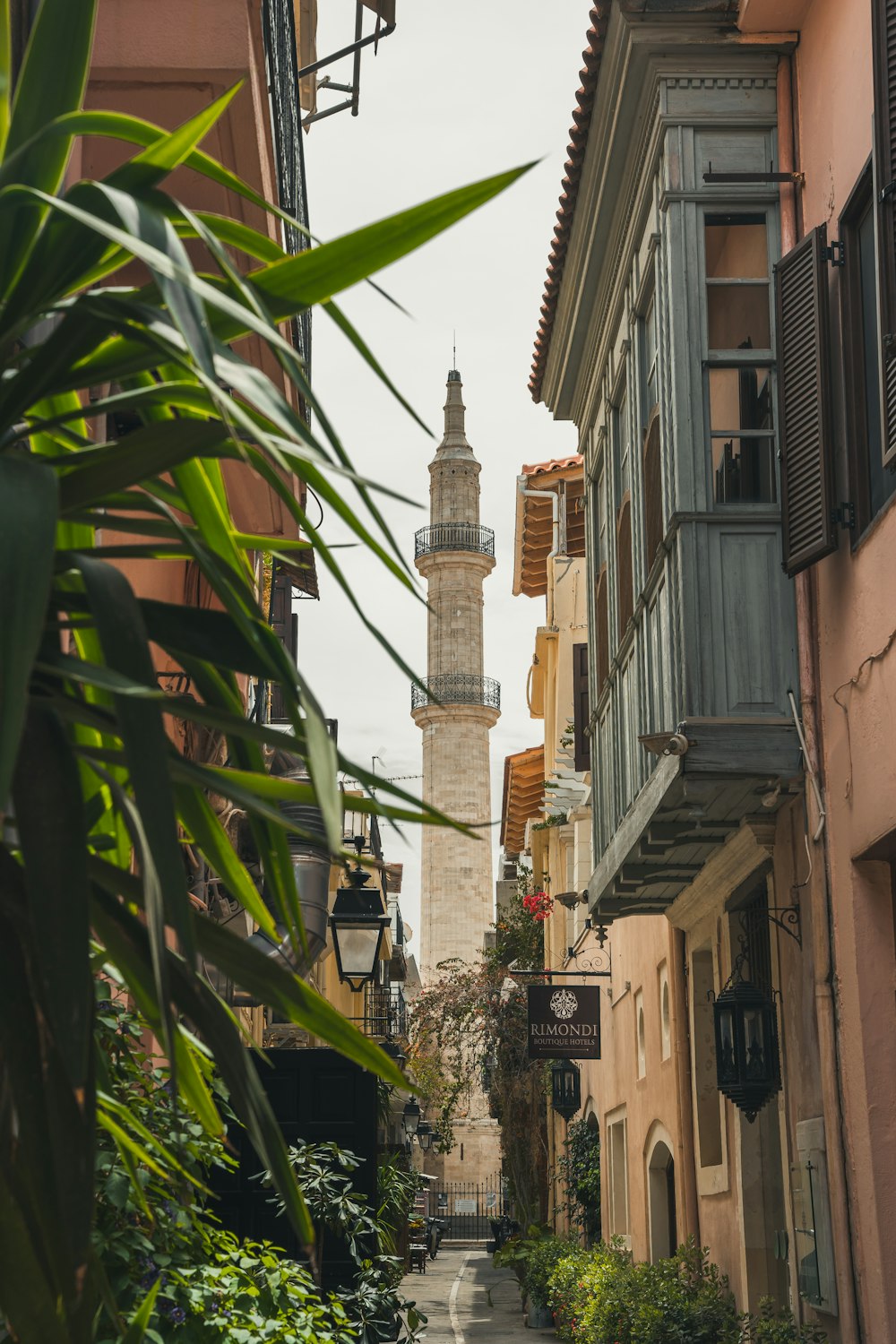 a narrow street with a tall tower in the background