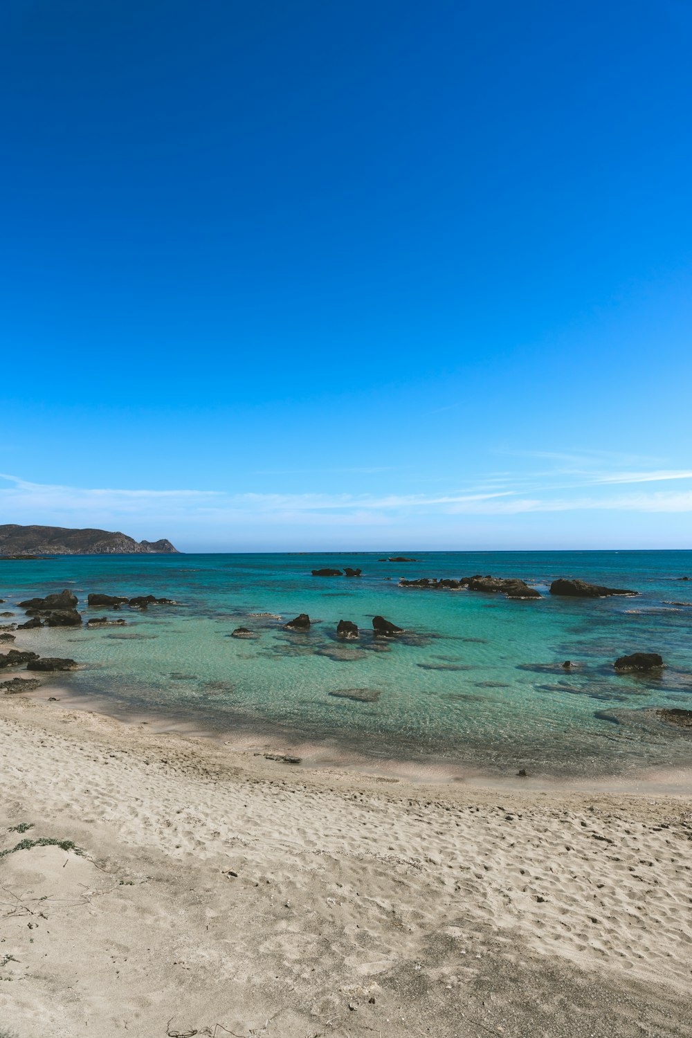 a sandy beach with clear blue water on a sunny day