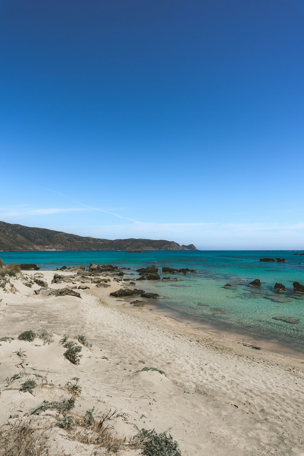 a sandy beach with clear blue water on a sunny day