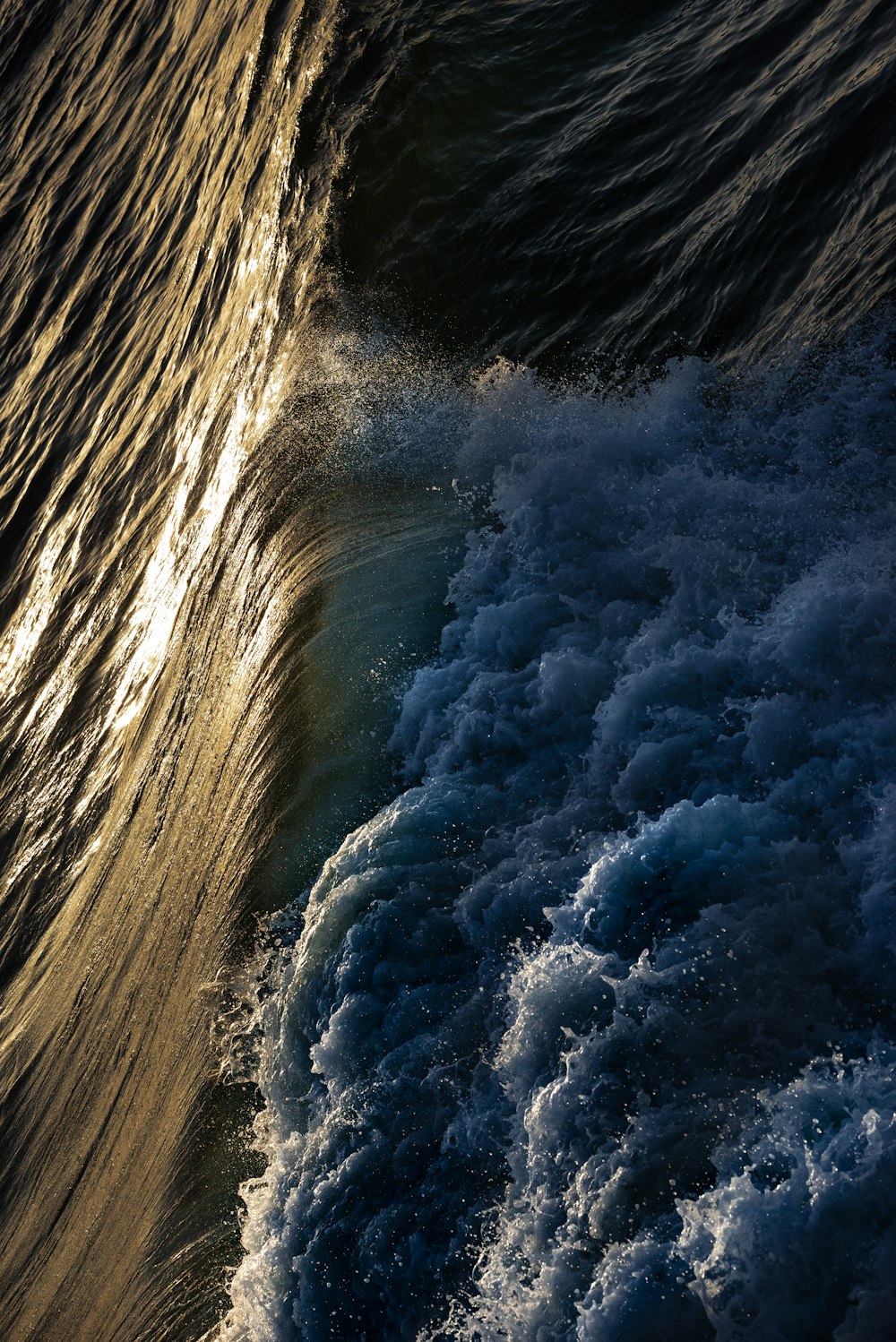 the sun shines on the water as it breaks behind a wave