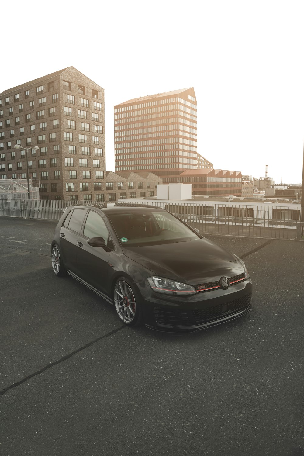 a black car parked in a parking lot next to tall buildings