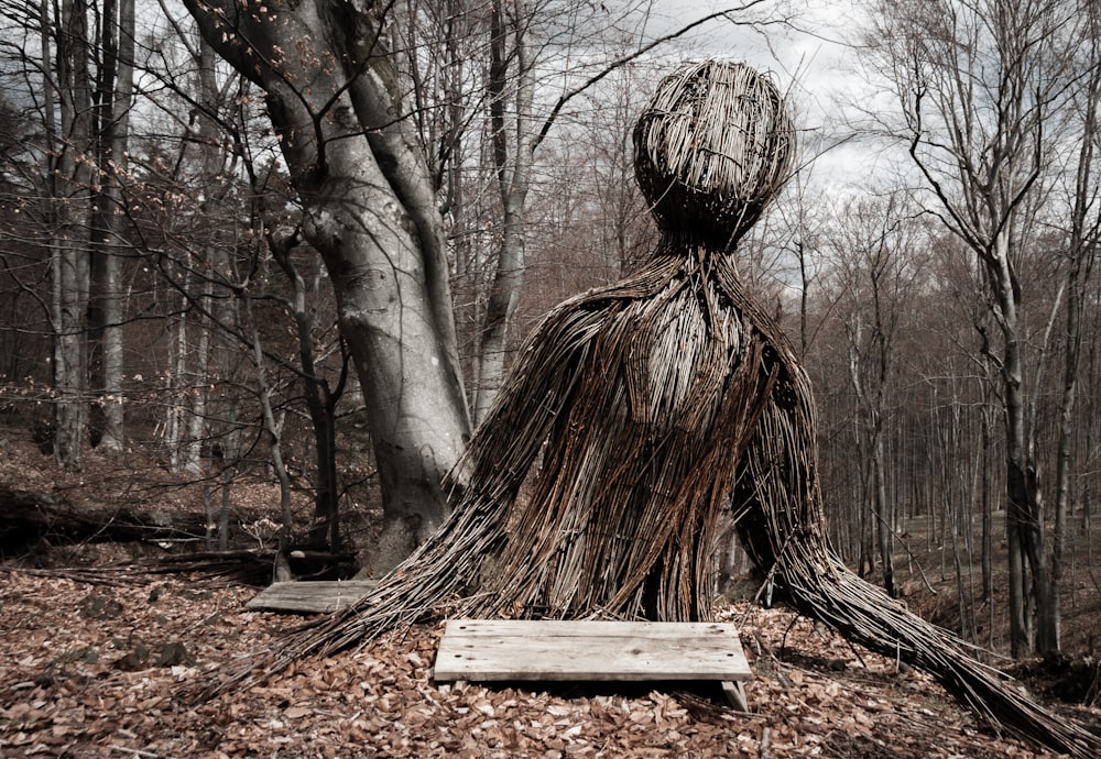 Una escultura de una persona parada en el bosque