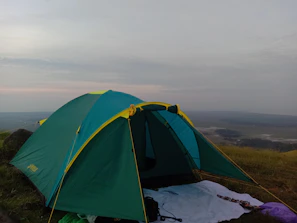 Close-up of hands setting up a tent with branded camping gear visible.