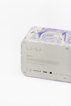 A rectangular electronic device with a marbled design on the top and sides, consisting of shades of purple, white, and beige. The front panel of the device is gray with various buttons, ports, and text, including a brand name and product information.