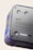 A close-up view of a device featuring a smooth metallic surface with buttons and text. The casing has a colorful marbled pattern. The text includes branding and a message about using recycled materials.