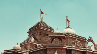 Intricately carved domes and spires of BAPS Swaminarayan Mandir floating on a soft cloud backdrop.